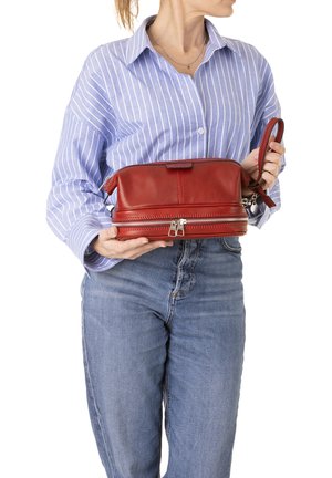 Borsa a tracolla in pelle rossa con parte superiore arrotondata, doppia zip e tracolla rimovibile. Texture liscia con dettagli minimi e accenti in hardware argentato.