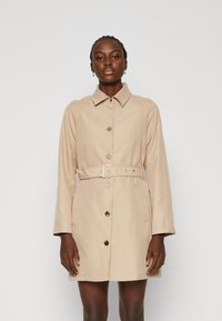 Cappotto trench beige con colletto, bottoni frontali, cintura e tasche laterali. Tessuto liscio e taglio dritto che termina a metà coscia.