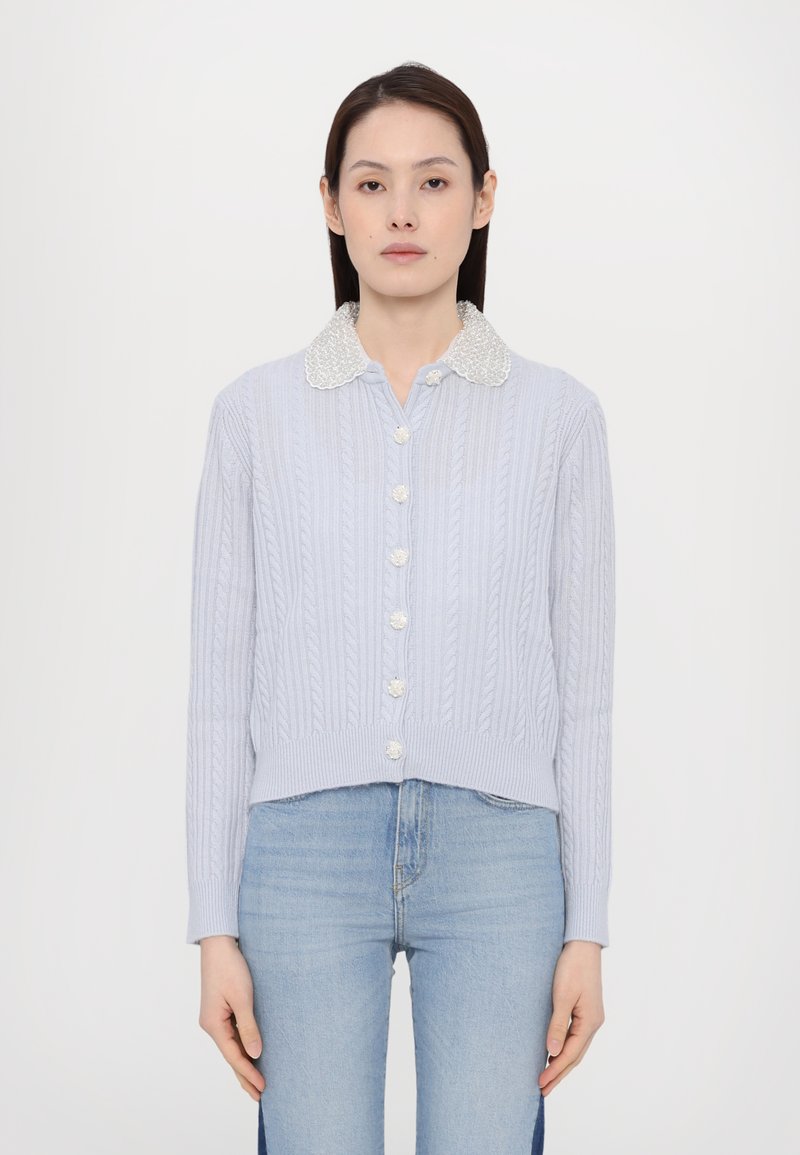 Cardigan a maglia color blu chiaro con colletto bianco decorato da perline e bottoni simili a perle, con design cropped e orlo e polsini a coste.