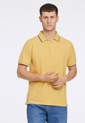 Gul polo skjorte med krave, der har en to-knaps knaplukning og kontrasttrim ved ærmerne. Simpelt logo broderet på brystet.
