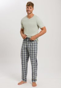 Lichtgroene v-hals t-shirt gecombineerd met geblokte pyjamabroek in groen, marineblauw en wit. De broek heeft een tailleband met trekkoord en een losse pasvorm.