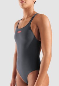 Musta harmaa yksiosainen uimapuku, jossa on ohuet hihnat ja punainen "arena"-logo rinnassa. Sileä kangas ja tiukasti istuva muotoilu.