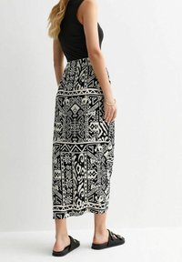 Maxi sukně v černobílé geometrické tisku, s volným designem a vzorovanou texturou, s pevným pasem.