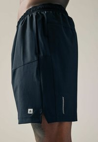 Shorts de sport de culoare bleumarin cu talie elastică, buzunare laterale și o mică etichetă cu logo cu detalii reflective pe margine.