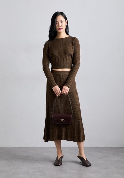 Brown ribbed knit top and matching skirt with a cropped design. A dark burgundy handbag with a chain handle. Pointed brown mules.