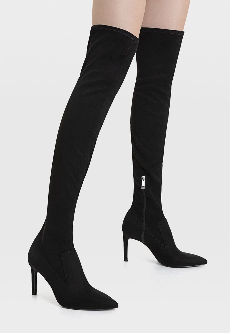 Black over-the-knee boots in soft suede with pointed toe and stiletto heel. Features a side zipper for easy wear.