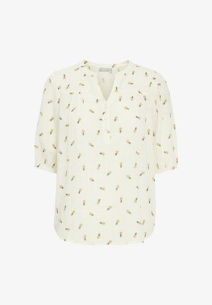 Blouse blanche avec des motifs de ananas jaunes. Présente un décolleté en V, une patte de boutonnage à trois boutons et des manches trois-quarts avec des poignets élastiques.