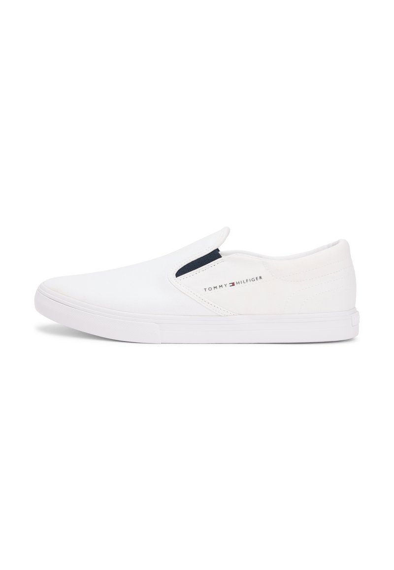 Άσπρα sneakers slip-on κατασκευασμένα από καμβά με λεία υφή και αντιθετική σκουρό μπλε λεπτομέρεια στο ελαστικό πλάι. Διαθέτουν ελαστική σόλα από καουτσούκ.