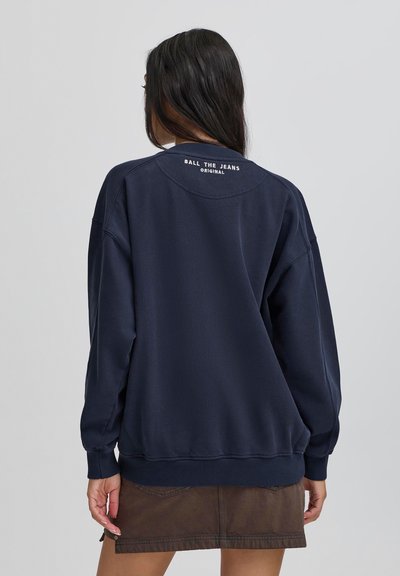 Námornícky sveter s uvoľneným strihom, rebrovanými manžetami a spodným okrajom. Na zadnej strane goliera je vyšité "BALL THE JEANS ORIGINAL".