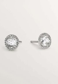 Pendientes de stud de cristal transparente facetado, rodeados por un ajuste en tono plateado con pequeños rhinestones claros, que cuentan con un cierre de tipo post-back.