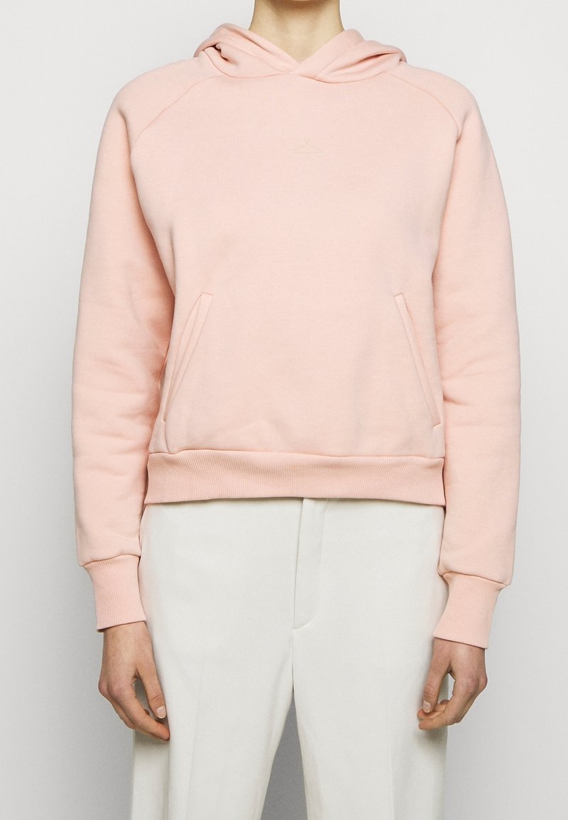 Rosa hoodie i mjukt material med en kanguroficka, ribbad manschett och nederkant. Har en liten logotyp ovanför bröstet och en huva med dragsko.