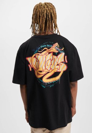 T-shirt noir avec un design graphique coloré au dos, comportant un texte entrelacé, un serpent et des formes abstraites. Manches courtes et coupe décontractée.