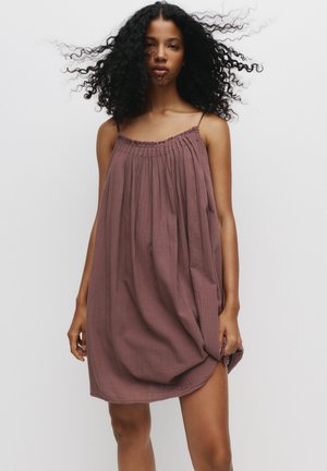 Loose-fitting, sleeveless dress in mauve, made of textured fabric. Features gathered neckline and a flowing silhouette, reaching mid-thigh.