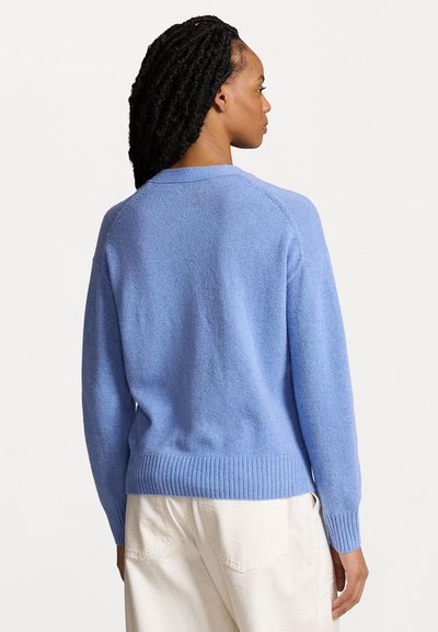 Gaiši zilas džemperis, izgatavots no tekstūrēta adījuma, ar ribotu apakšmalu un piedurknēm, relaksējoša piegriezuma un raglāna piedurknēm.