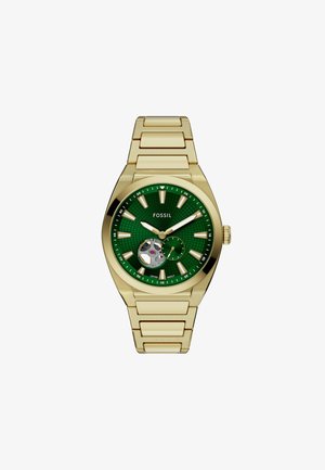 Orologio dorato con un quadrante verde texturizzato, tre sotto-quadranti e indici delle ore luminescenti. Presenta un robusto bracciale in metallo.