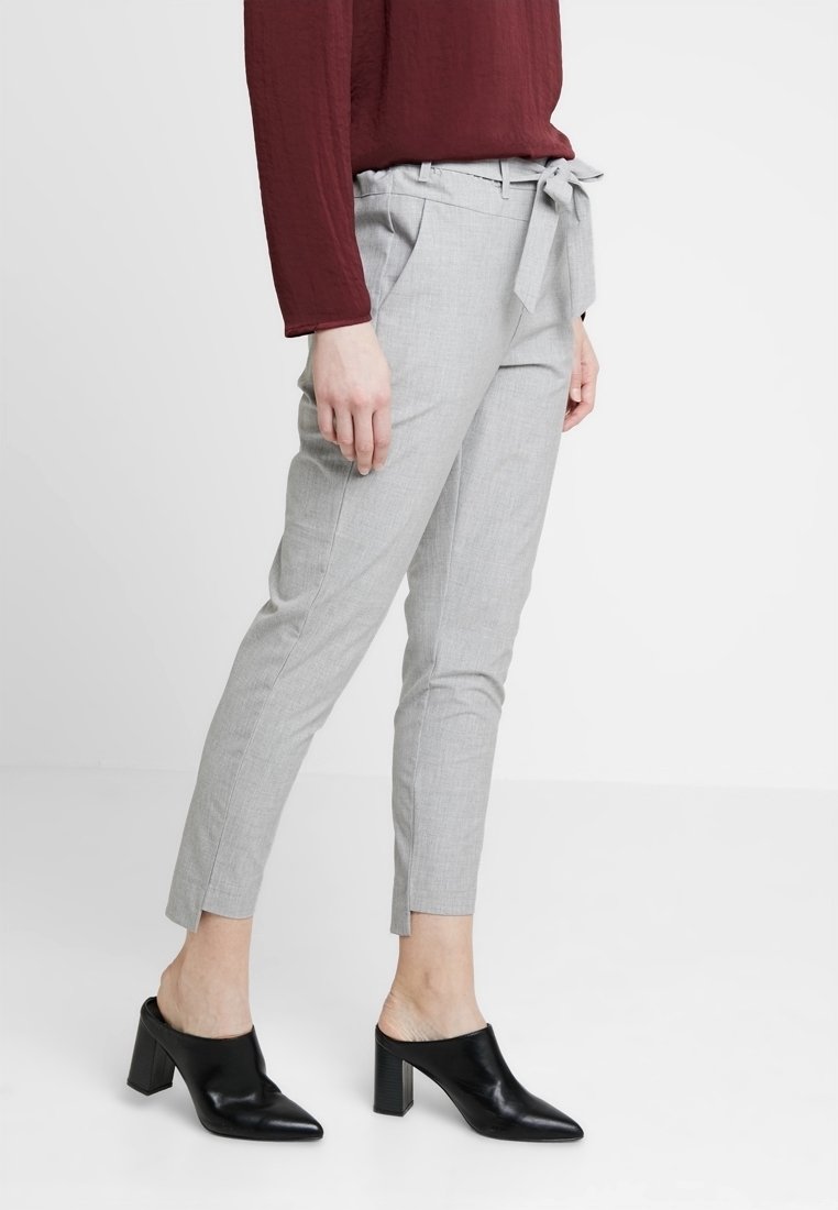 Pantalons gris ajustés avec une ceinture nouée et des poches latérales, associés à des mules à talons noirs. Tissu lisse avec une coupe élégante.