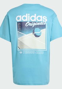 Svijetloplava pamučna majica s oversize krojem. Grafički print s loptom za tenis i terenom. Tekst "adidas Originals" i "TENNIS CLUB" u bijeloj boji.
