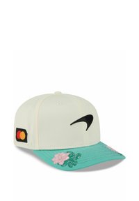 Mütze mit einem cremefarbenen Körper, mintgrünem Schirm, verziert mit pinken Blumenstickereien, schwarzem Nike-Logo und einem kleinen bunten Mastercard-Tag an der Seite.