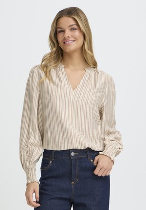 Cream-colored blouse with vertical red stripes, V-neckline, gathered shoulders, and elastic cuffs. Worn with dark denim jeans.