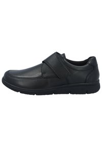 Schwarzer Lederschuh mit niedrigem Profil, runder Zehenform und breitem Klettverschluss. Texturiertes Obermaterial mit gummierter Sohle für Grip und Komfort.