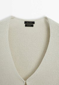 Off-White Baumwollstrickjacke mit tiefem V-Ausschnitt, gerippter Textur und Knopfverschluss. Verfügt über sichtbare Nähte und ein dezentes Markenetikett.