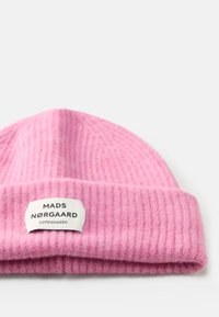 Beanie a coste rosa con risvolto, caratterizzato da un'etichetta bianca con la scritta "MADS NØRGAARD COPENHAGEN" stampata in nero. Texture morbida.