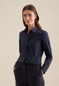 Navyblauwe, langärmelige blouse met knopen en een puntige kraag, gemaakt van gladde stof en met een getailleerde pasvorm en zakdetails.