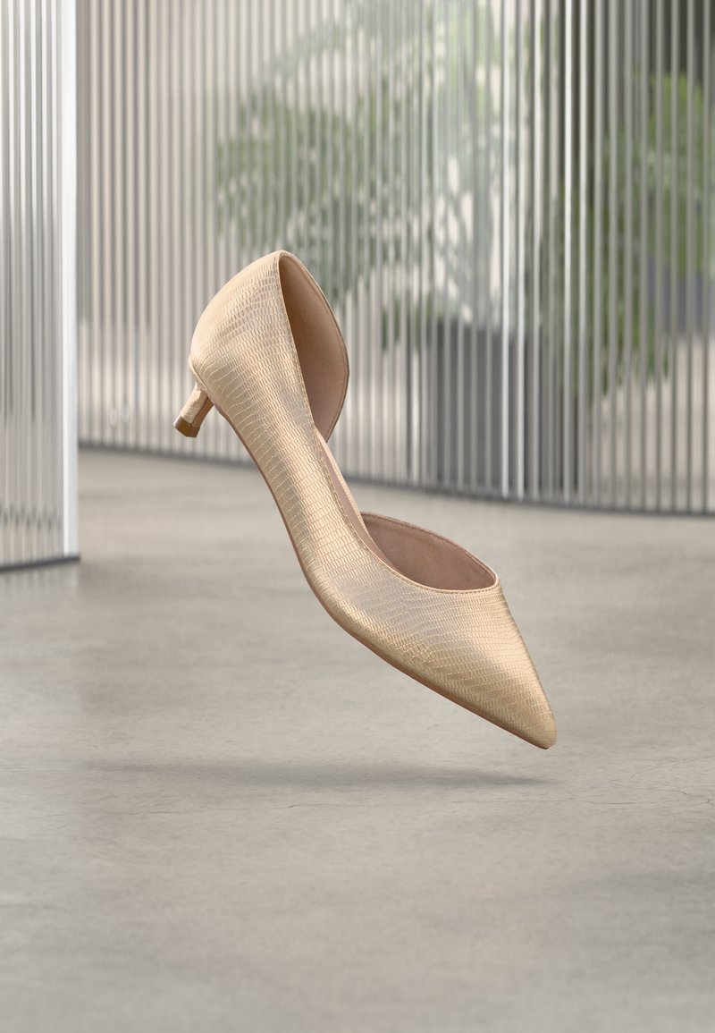 Μπεζ ψηλοτάκουνο παπούτσι με μυτερή μύτη, υφή στην επιφάνεια, κοντό τετράγωνο τακούνι και ανοιχτή πίσω πλευρά, παρουσιασμένο σε μινιμαλιστικό φόντο.