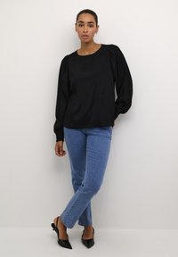 Black satin blouse with puff sleeves, round neckline, paired with light blue denim jeans and black pointed-toe heels.