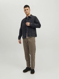 Tume teksatagi eest taskutega, must alt kaelusega särk, beežid püksid tekstuursete detailidega ning mustad kingad beežide tallaga.