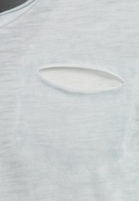 Helles blaues Kurzarmhemd mit einer Tasche mit ovalem Ausschnitt. Der Stoff ist glatt mit einer subtilen Struktur und leichtem Glanz.