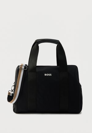 Černá taška typu tote s dvojitými rukojetmi a odnímatelným ramenním popruhem. Má elegantní design, stříbrné logo a kontrastní pruhované detaily.