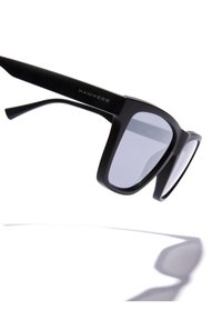 Ochelari de soare rectangulari negri cu finisaj mat, având lentile gri, cadru elegant din acetat și temple unghiulare cu marca 'HAWKERS'.