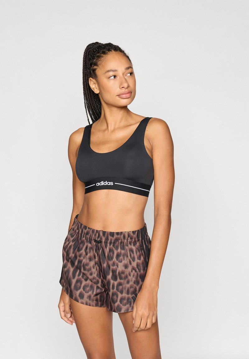 Zwart sportbeha met logo en gestreepte band, gecombineerd met bruine short met luipaardprint met een elastische tailleband en trekkoord.