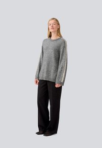 Gray wool sweater with a round neckline and patterned sleeves, paired with black wide-leg trousers. Smooth texture, relaxed fit.