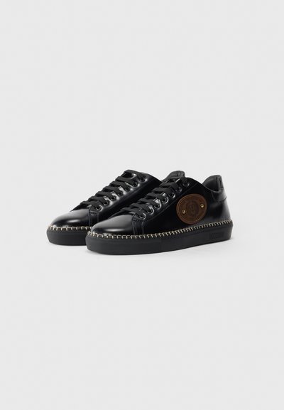 Schwarze Leder-Sneaker mit ovaler Zehenpartie, genähten Details, einem hellbraunen Logo-Patch und Gummisohle. Schnürdesign mit sechs Ösen.