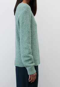 Mintgrüner Pullover mit strukturiertem, flauschigem Finish. Mit gerippten Bündchen und Saum sowie einem lässigen Schnitt. Trägt man über dunklen Hosen.