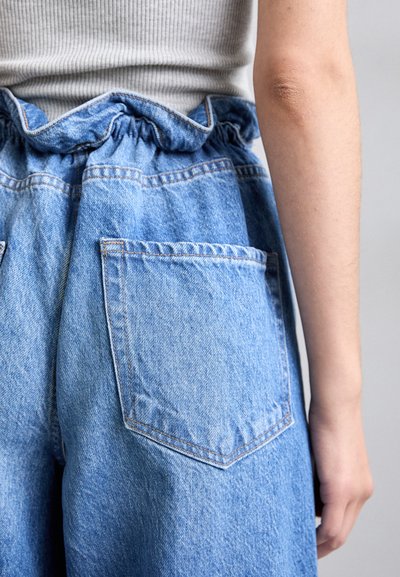 Αρκετά μπλε τζιν παντελόνι με  gathered waistband και δύο πίσω τσέπες. Το ύφασμα έχει μια διακριτική υφή και λεπτομέρειες ραφής.