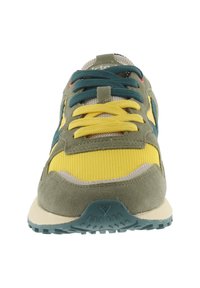 Zapatilla multicolor con ante verde oliva, malla amarilla y cordones teal. Diseño ligero notable con detalles texturizados y suela de goma.