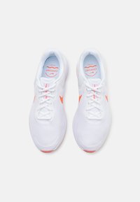 White athletic shoes with pink accents, mesh upper, round toe, lace-up closure, cushioned insole, and rubber outsole for traction.