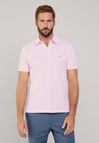 Polo shirt in lichtroze katoen met een klassieke kraag, korte mouwen en een klein geborduurd blauw logo op de borst.