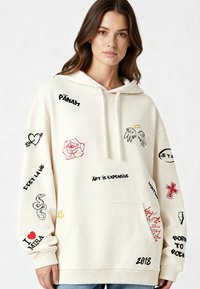 Felpa color crema con vari design ricamati, tra cui fiori, cuori e frasi in rosso e nero. Presente tasca a canguro frontale.