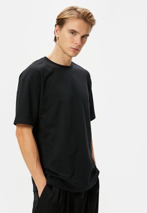 Sort bomulds T-shirt med rund halsudskæring, korte ærmer og en afslappet pasform. Stoffet fremstår glat og blødt uden synlige mønstre.