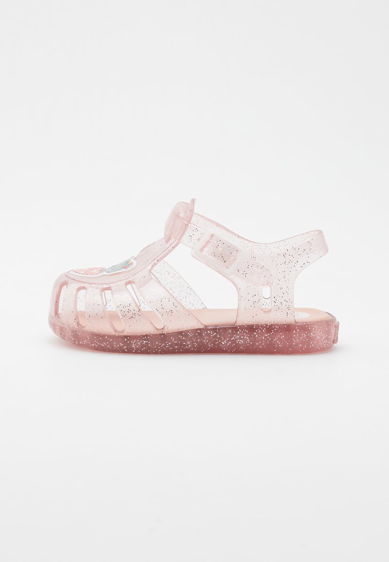 Sandalia de gel rosa clara con destellos, diseño abierto que presenta recortes, correa ajustable y plantilla suave. Punta redondeada y suela plana.