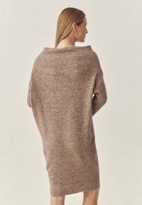 Übergroßer brauner Strickkleid, weiche Textur, lockere Passform, weiter Ausschnitt und lange Ärmel, die bis zur Oberschenkelmitte reichen.
