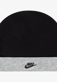 Čierna pletená čiapka s sivým lemom, na prednej strane s malým čiernym logom Nike. Textúra je mäkká a pružná.