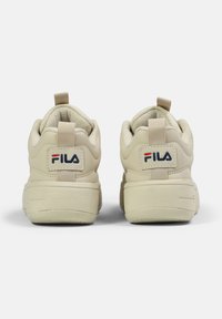 Sneakers FILA beige con retro testurizzato, colletto imbottito e linguetta. Presentano una patch con il logo e un design con suola spessa.