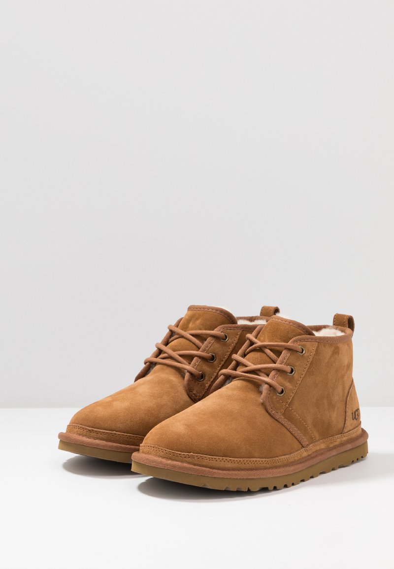 Brown suede ankle boots with lace-up design, rubber sole, cushioned interior, and a soft lining. Features logo on the side.