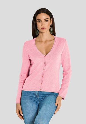 Rosa Strickjacke aus weichem Stoff, mit V-Ausschnitt, langen Ärmeln und durchgehender Knopfleiste mit passenden Knöpfen, kombiniert mit blauen Jeans.