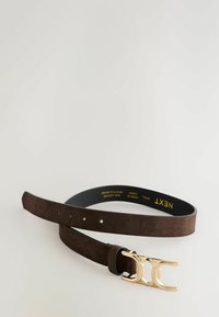 Bruine suede riem met zeven gaatjes en een gouden dubbele C-vormige metalen gesp, opgerold liggend op een witte ondergrond.